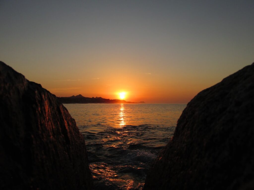 Woman in a peaceful yoga pose on a sandy Los Cabos beach during sunrise, embodying tranquility and wellness.