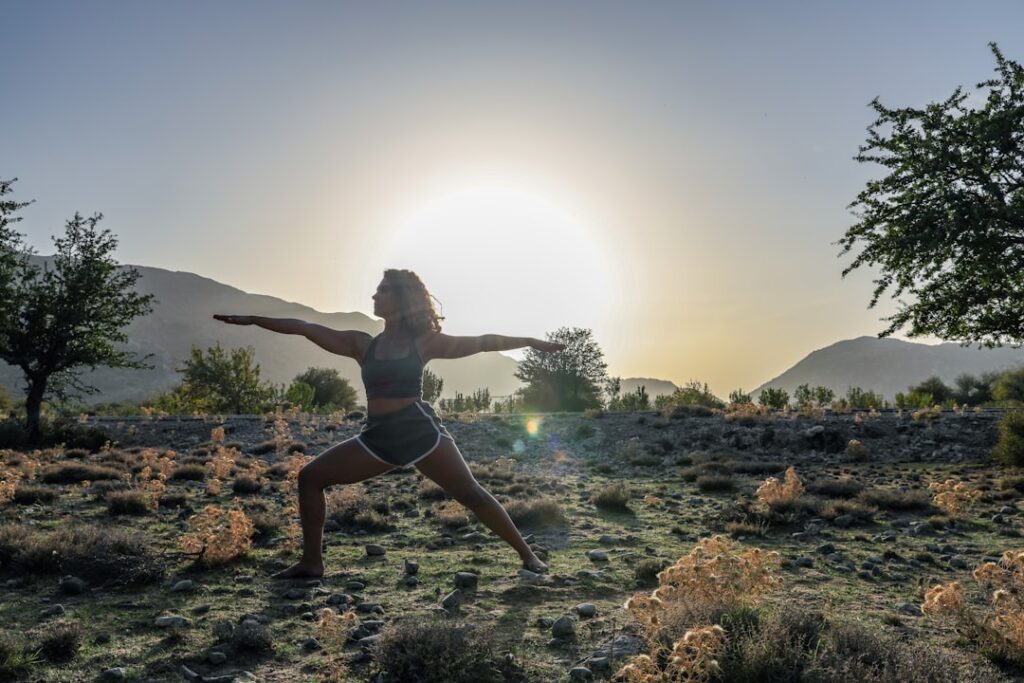 Woman in a tranquil yoga pose on a desert bluff overlooking the ocean at sunrise, embodying wellness in San José del Cabo.